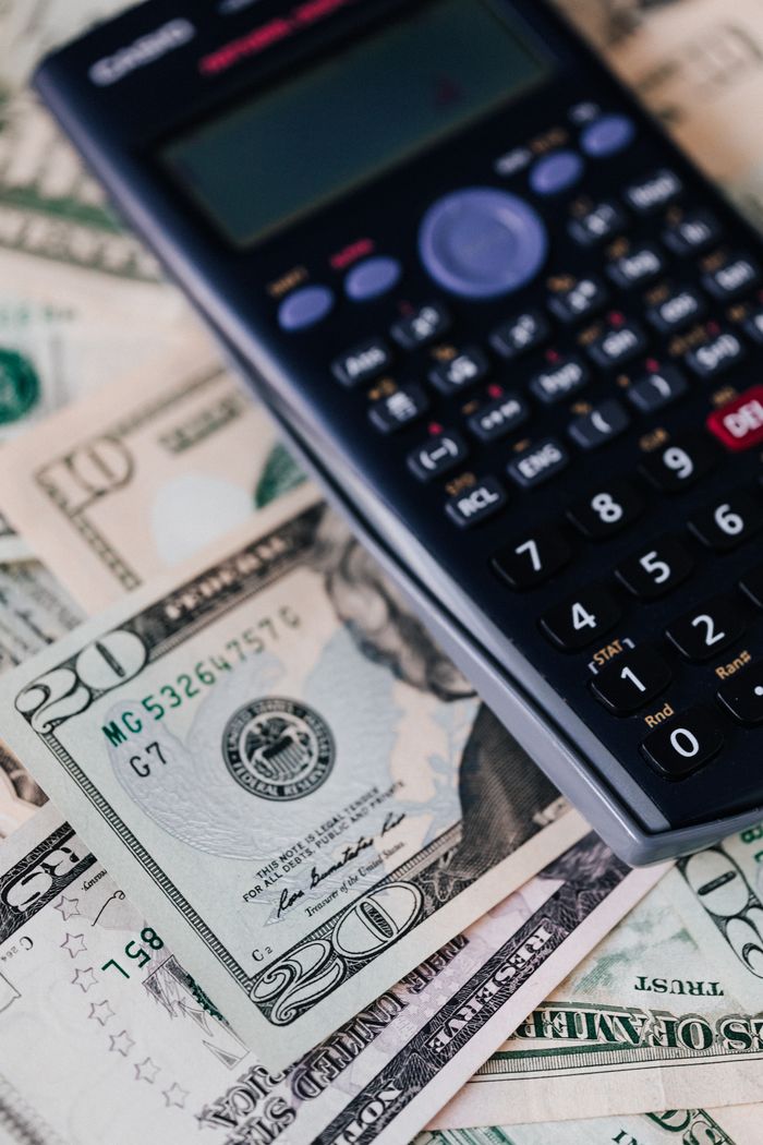 About From above of calculator placed on paper banknotes of American dollars on table