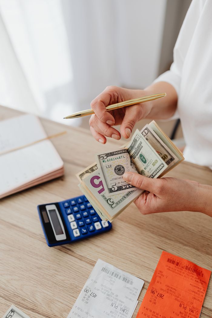 Services Woman counting money with calculator and receipts on a desk, planning budget.